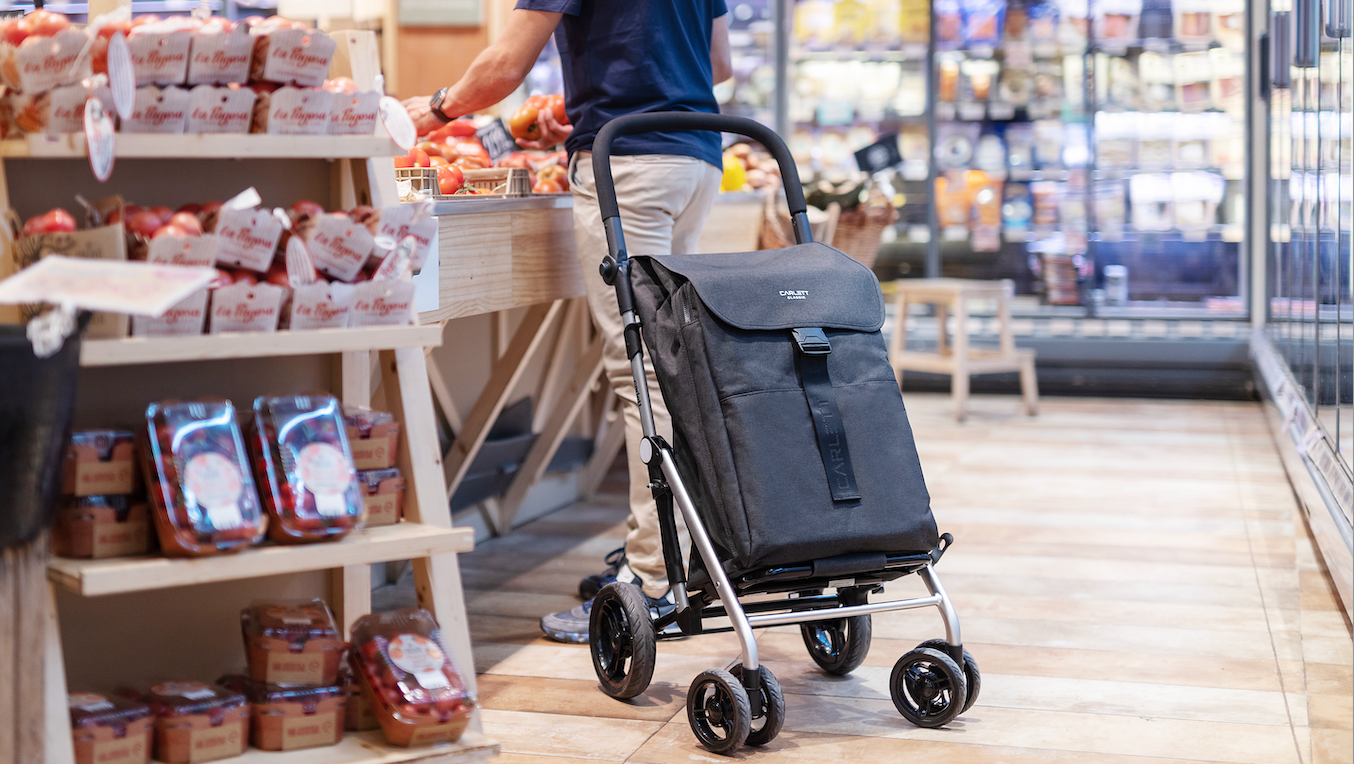 Persona comprando con carro de la compra Carlett en supermercado ecológico, ideal para una compra responsable